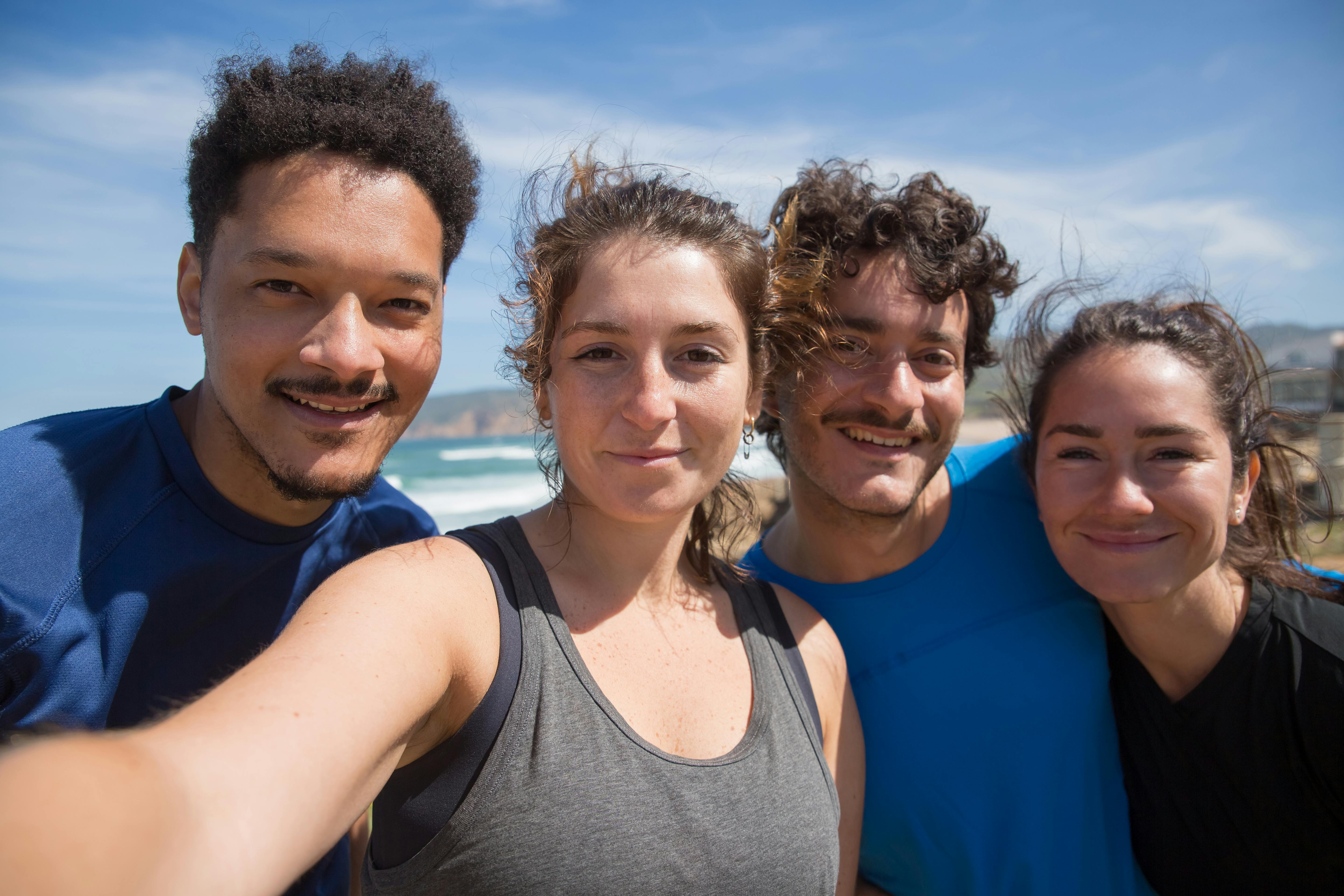 Real photo of four friends taking a selfie on a sunny beach