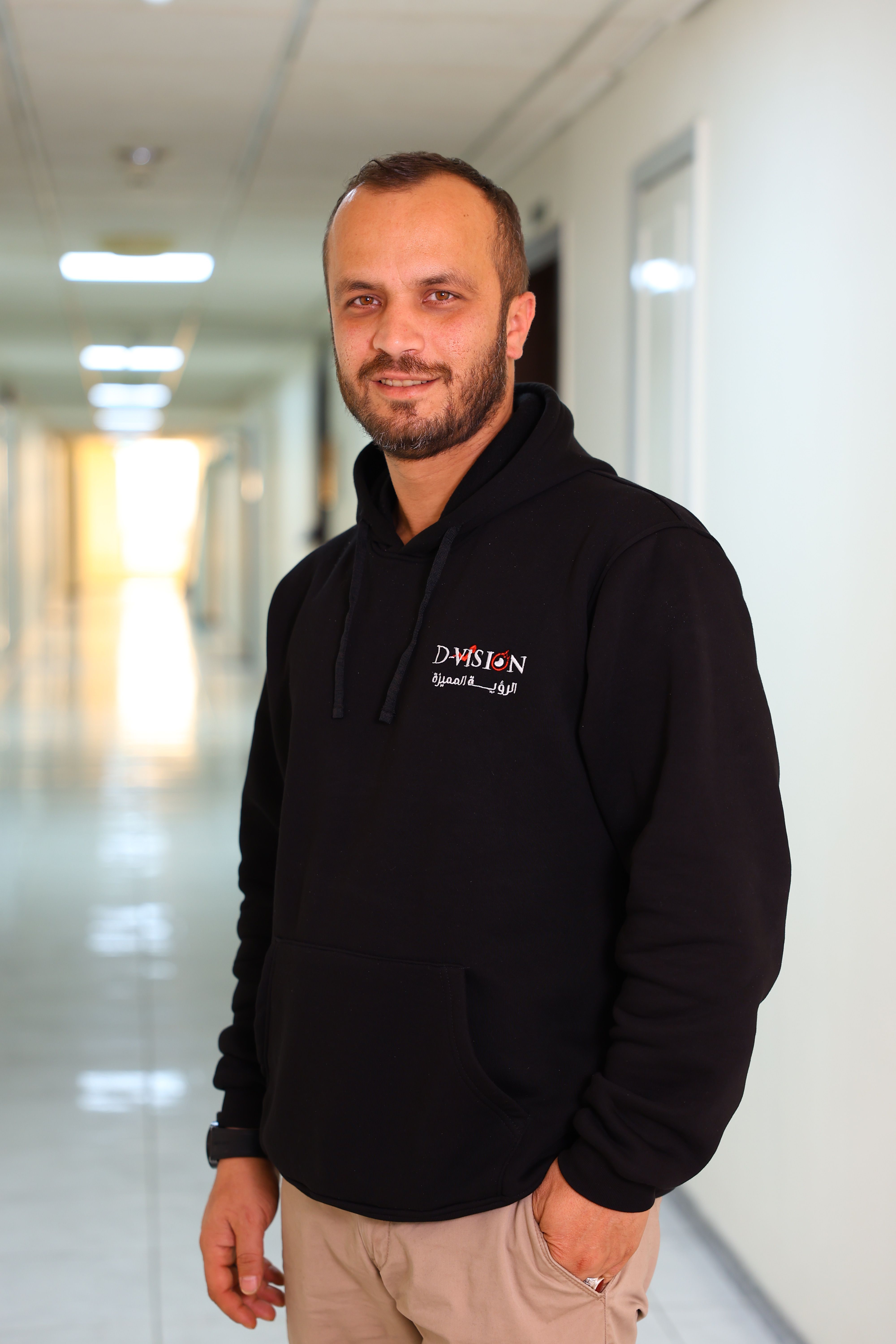 Real photo of a man wearing a black D-Vision hoodie in an office hallway